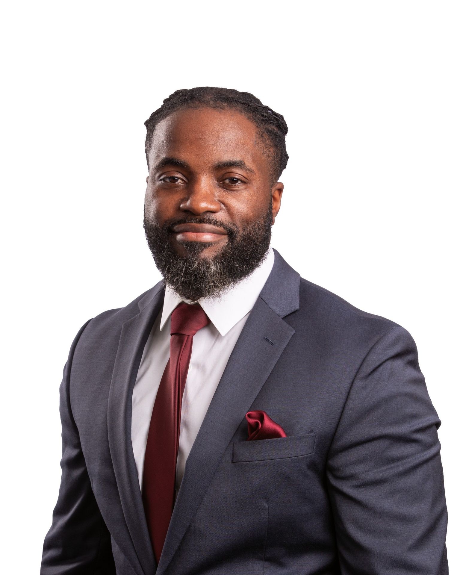 Man in a dark suit with a red tie and pocket square, smiling against a white background.