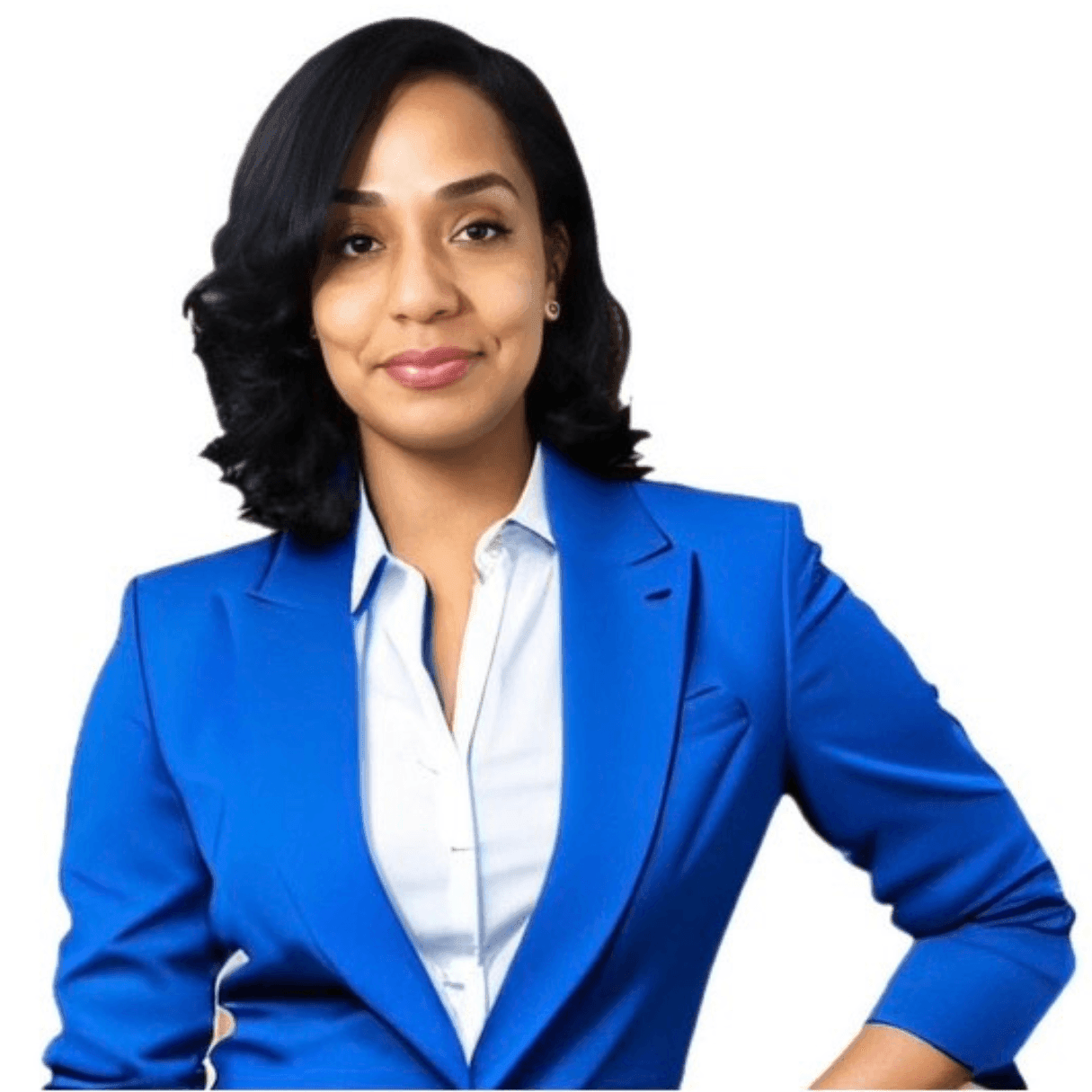 Person with curly black hair wearing a blue blazer and white shirt standing against a white background.